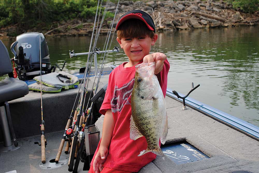 Little angler holds up a crappie fish.