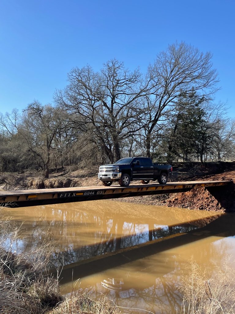 A truck crosses a bridge over a creek