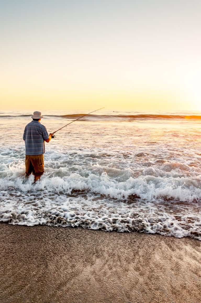 A man surf fishing at sunset